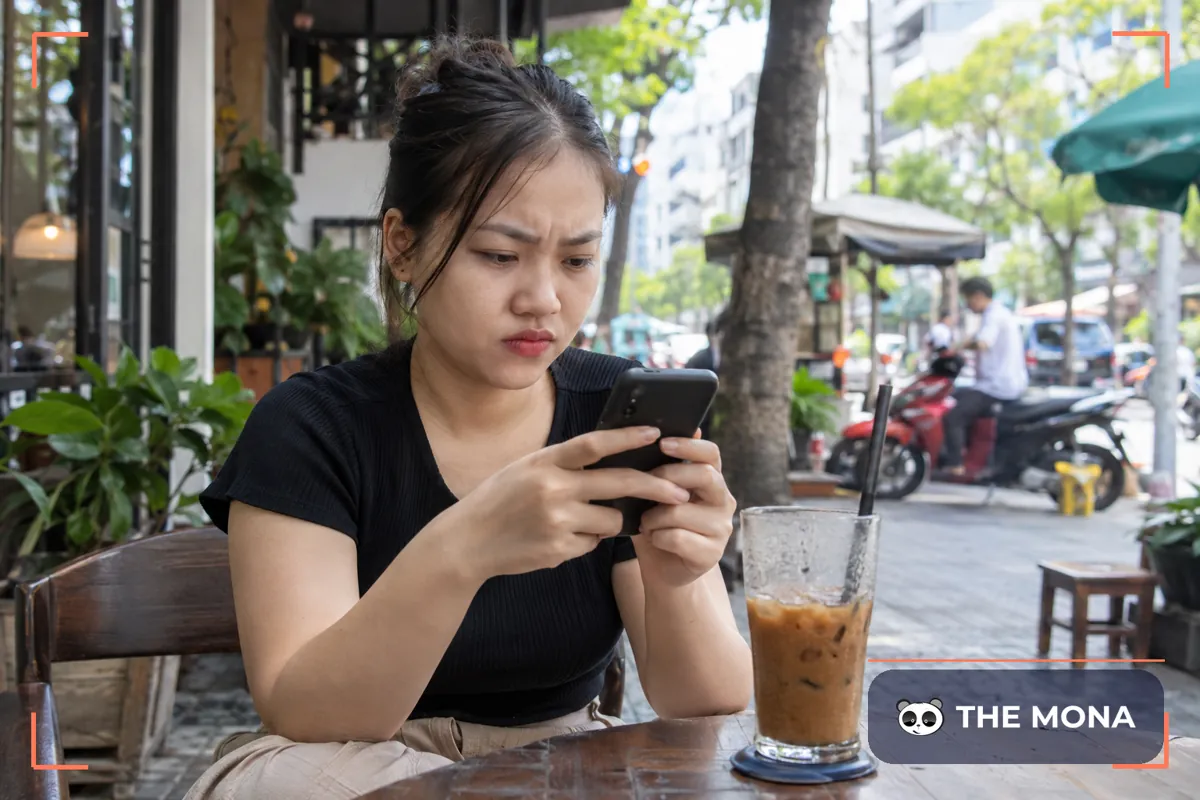 Khách ngồi quán cà phê lướt điện thoại so giá ở shop khác, vẻ sốt ruột