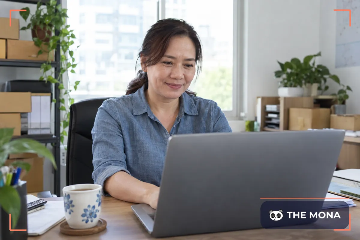 Chủ nhà phân phối thư thả xem bảng công nợ đã thu đủ trên laptop