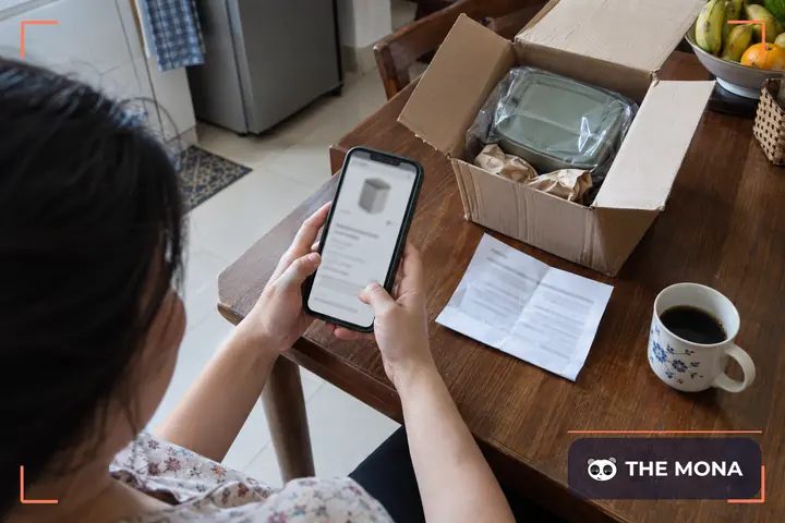 Người mua xem chính sách đổi trả trên điện thoại bên cạnh kiện hàng vừa mở