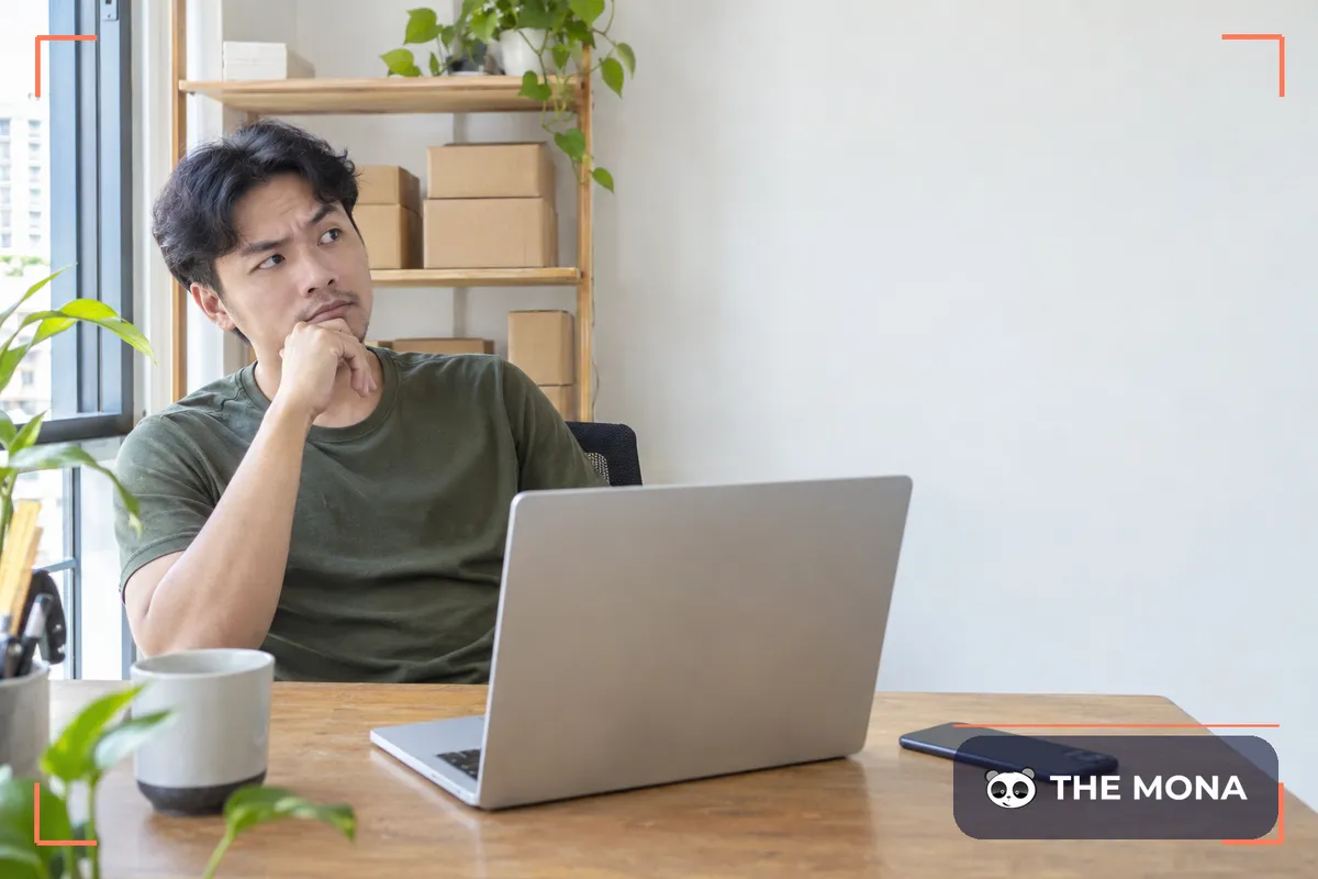 Chủ shop online ngồi trước laptop, tay chống cằm cân nhắc chọn chatbot bán hàng