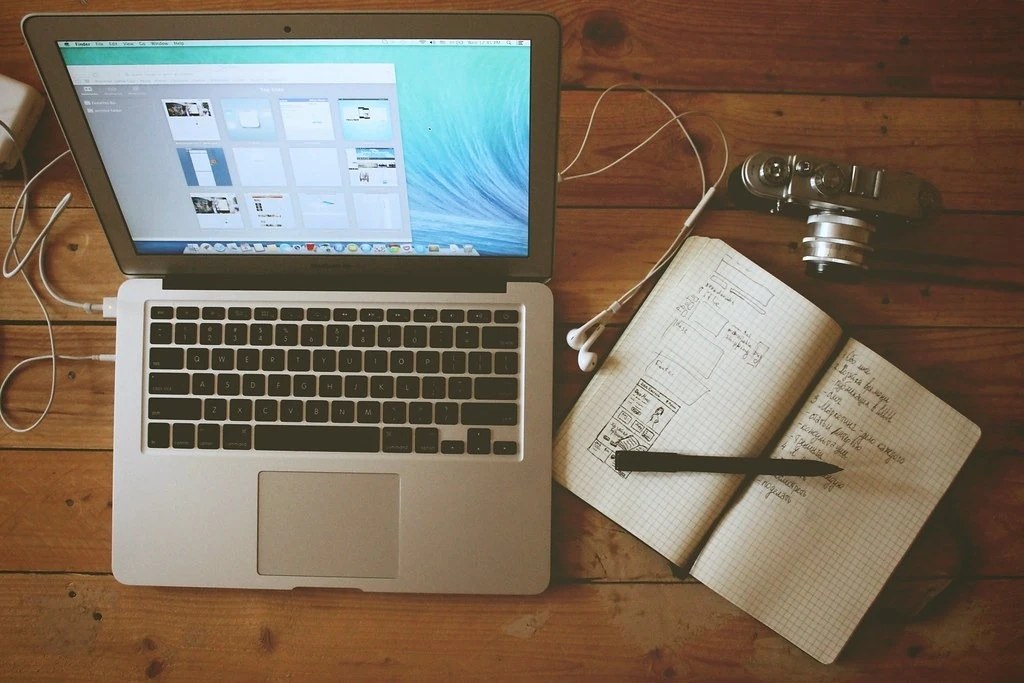 Laptop mở hộp thư cạnh cuốn sổ ghi chép trên bàn gỗ