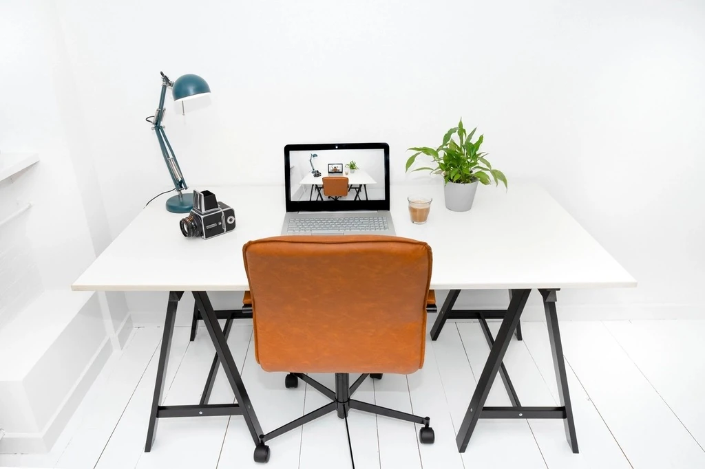 Bàn làm việc gọn gàng với laptop và ghế trong văn phòng sáng