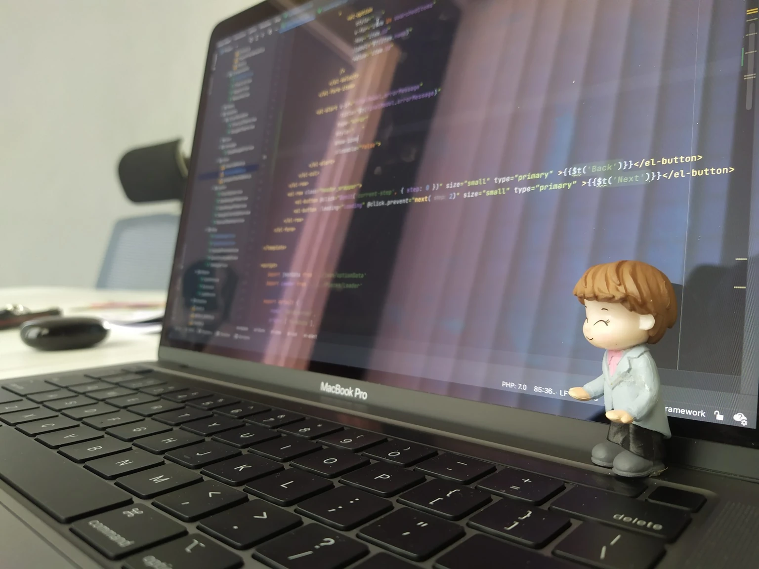 Màn hình MacBook hiển thị đoạn mã giao diện và một tượng nhỏ