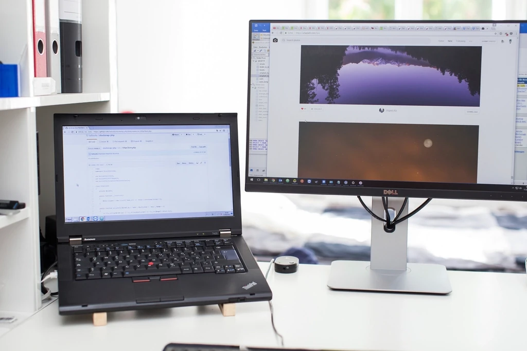 Bàn làm việc văn phòng với laptop đặt cạnh màn hình lớn trên mặt bàn trắng
